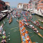 viele bunte Drachenboote mit pinken Paddlerinnen schwimmen in einem Lanal in Venedig